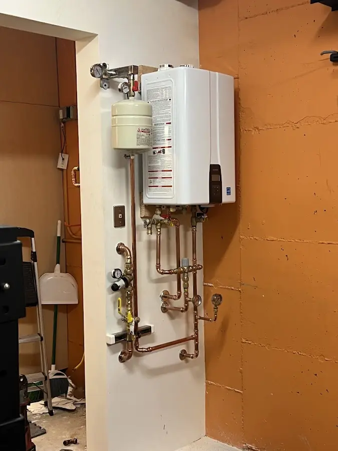 Plumbing technician inspecting water heater connections in West Salem